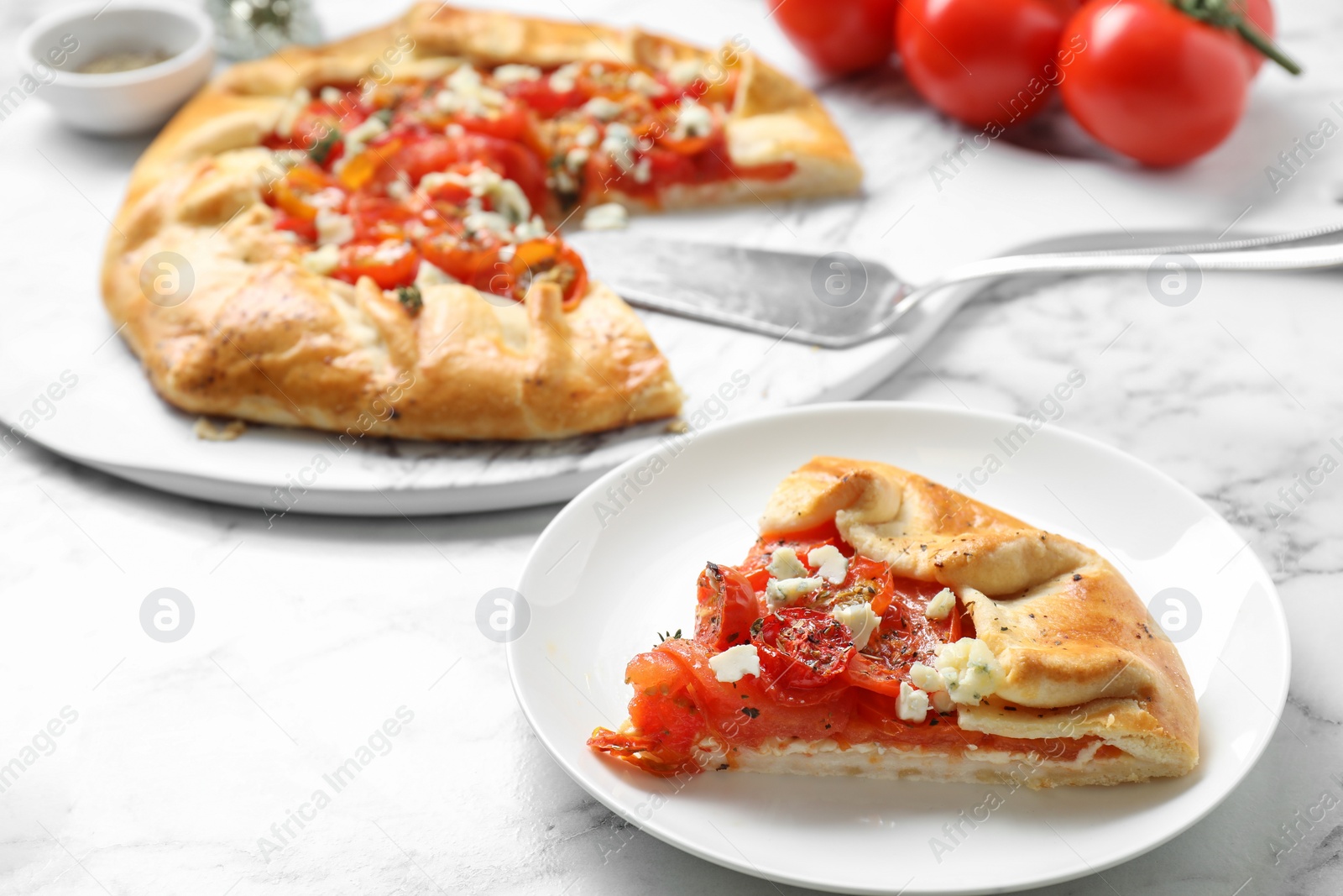 Photo of Tasty galette with tomato and cheese (Caprese galette) on white marble table, closeup