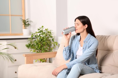 Photo of Woman drinking beverage on sofa at home