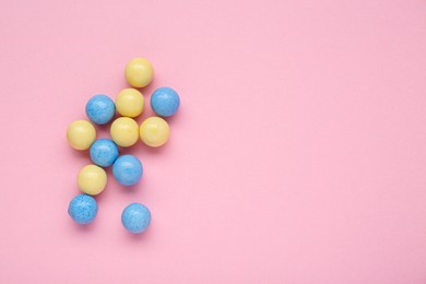 Many bright chewy gumballs on pink background, flat lay. Space for text