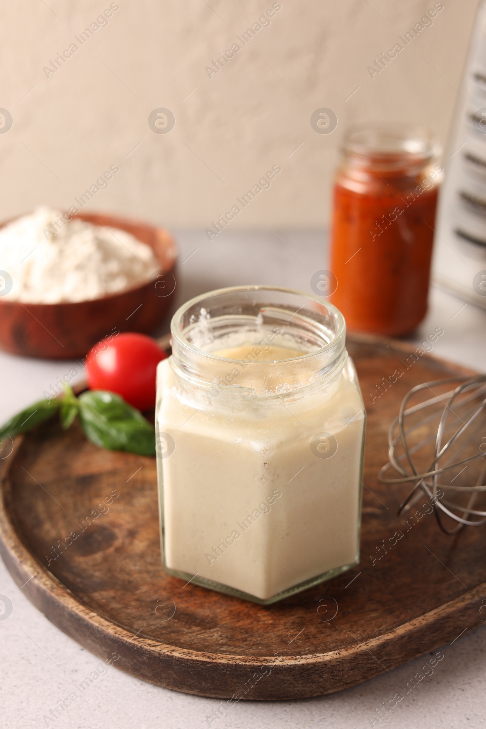 Photo of Pizza dough starter in glass jar and products on gray table