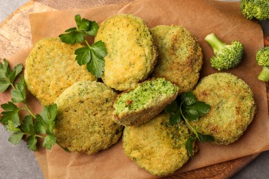Photo of Delicious vegan cutlets with broccoli and parsley on parchment paper, top view