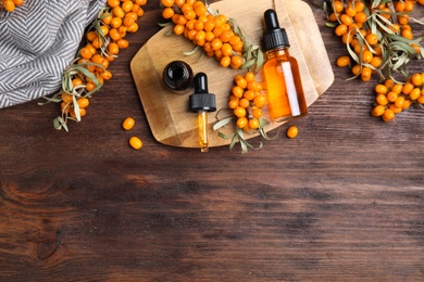 Photo of Flat lay composition with sea buckthorn oil on wooden table. Space for text