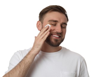 Photo of Happy young man applying facial cream on white background