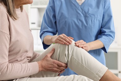 Photo of Arthritis symptoms. Doctor examining patient with knee pain in hospital, closeup