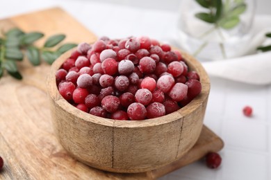 Frozen red cranberries in bowl on white table, closeup
