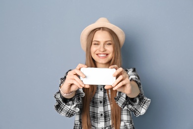 Photo of Young beautiful woman taking selfie against grey background