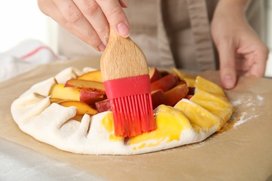 Woman making peach pie at kitchen table, closeup
