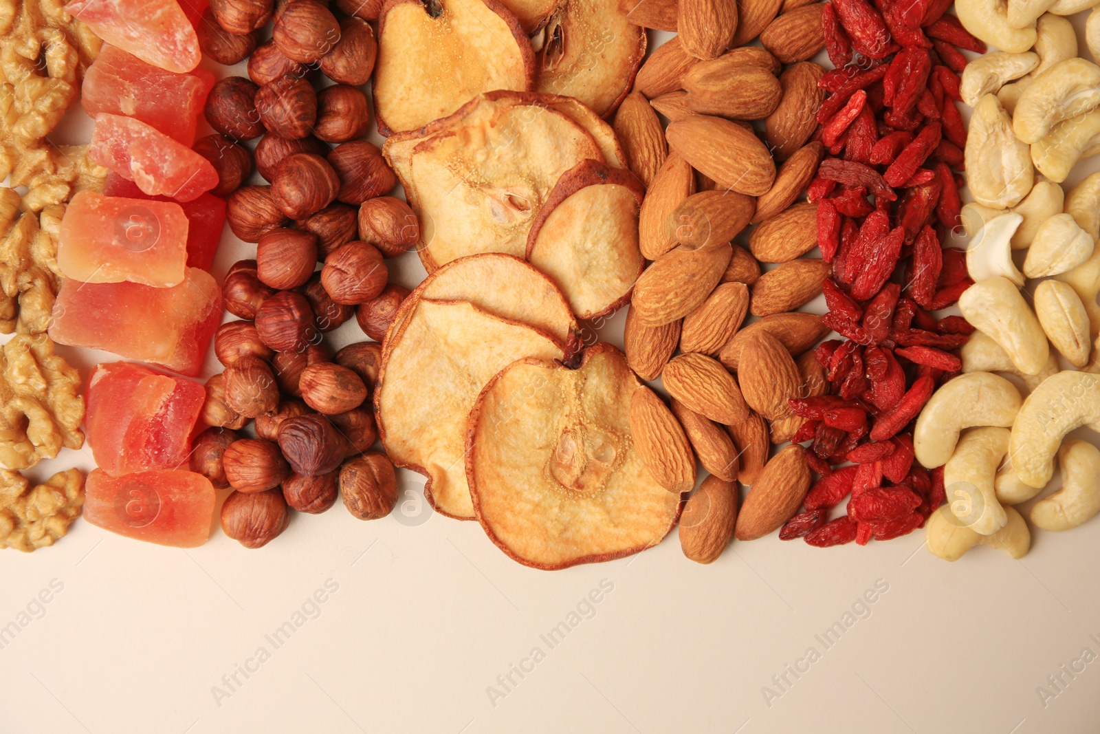 Photo of Mix of delicious dried nuts and fruits on beige background, flat lay