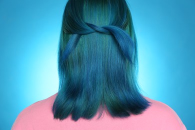 Photo of Woman with bright dyed hair on light blue background, back view