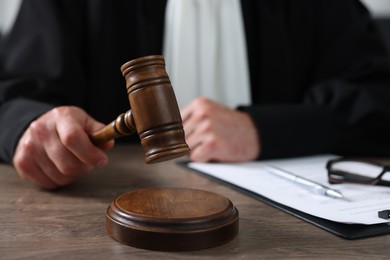 Photo of Judge with gavel and papers sitting at wooden table, closeup