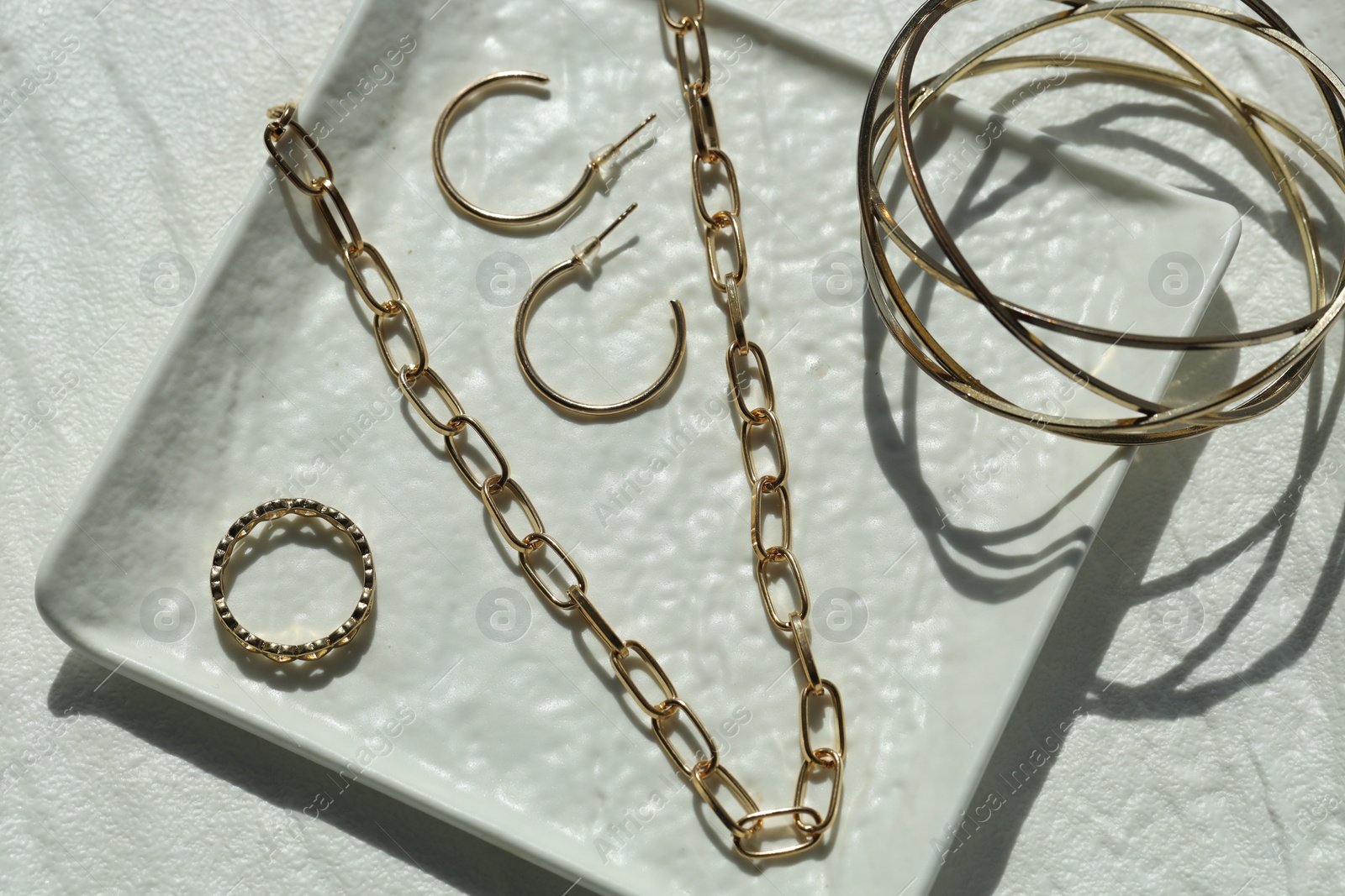 Photo of Metal chain and other different accessories on white table, flat lay. Luxury jewelry