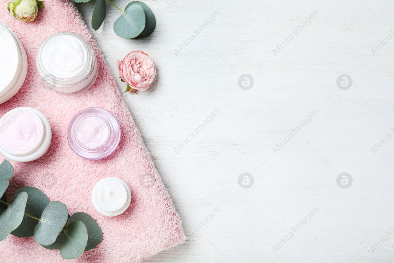 Photo of Flat lay composition with jars of cream on white wooden table. Space for text