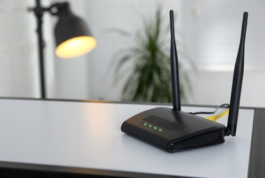 Photo of Modern Wi-Fi router on table indoors. Space for text