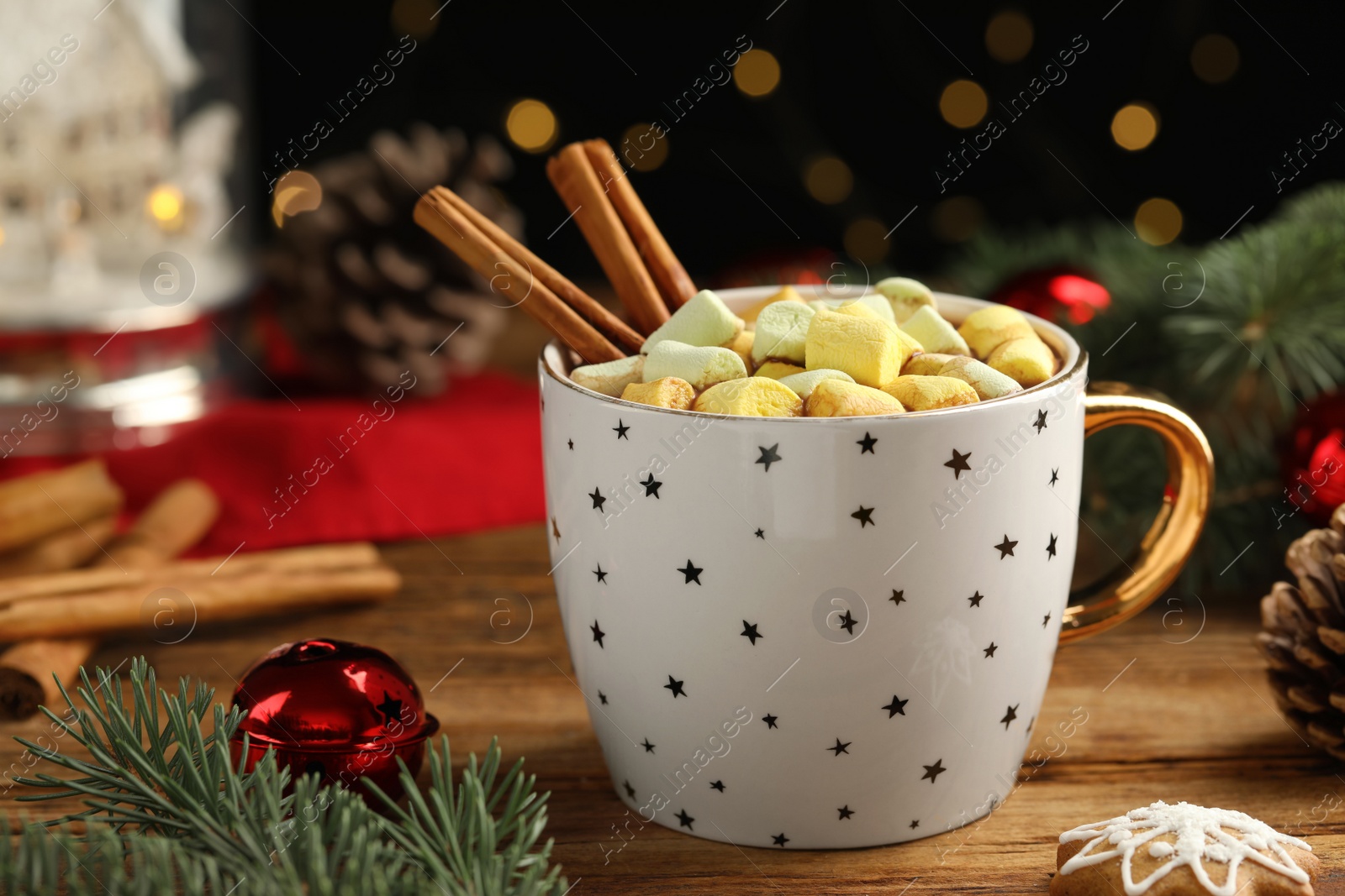 Photo of Delicious hot chocolate with marshmallows, cinnamon and Christmas decor on wooden table against blurred festive lights, closeup