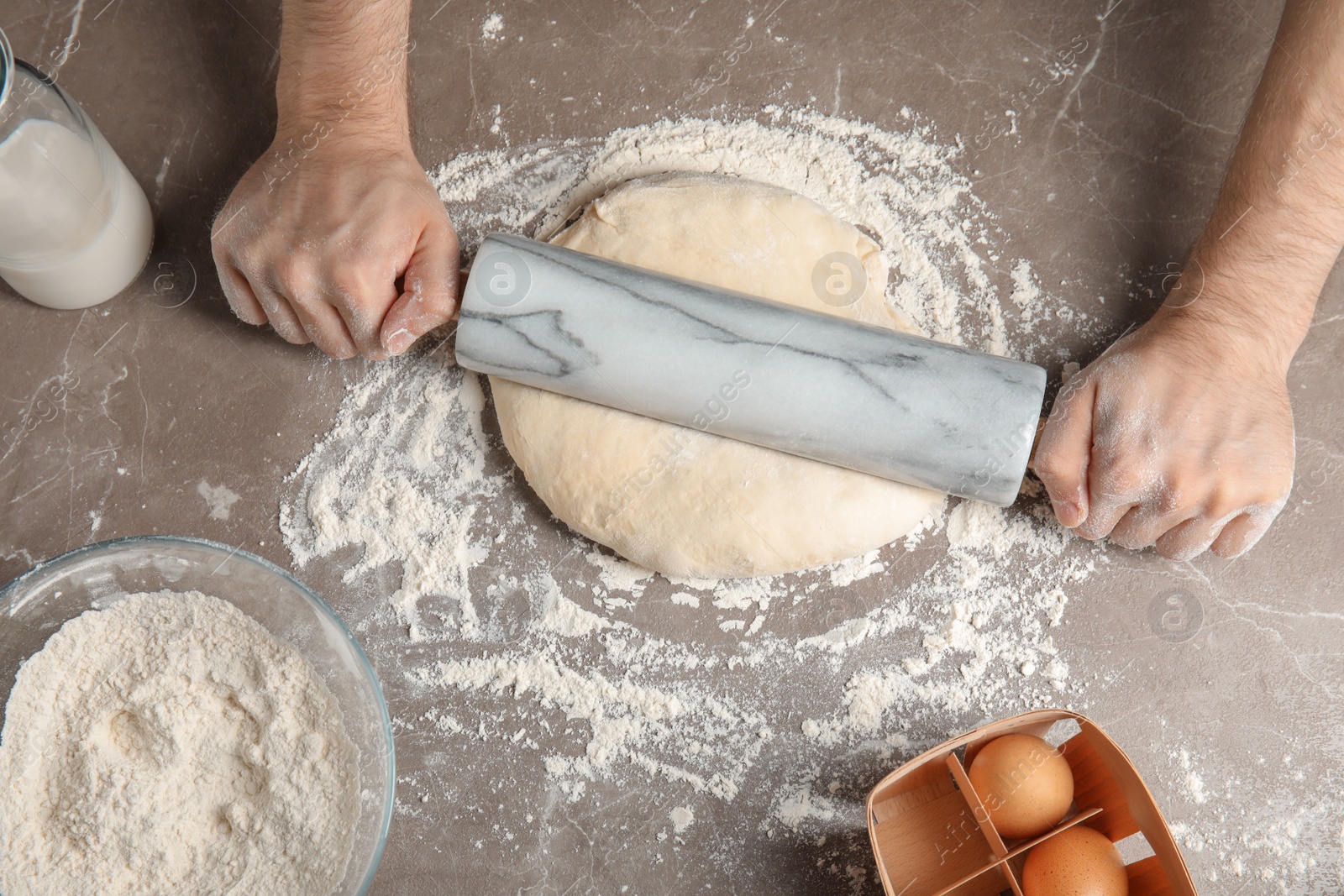 Photo of Man rolling dough for pizza on table