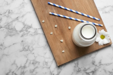 Bottle of milk and straws on light background, top view