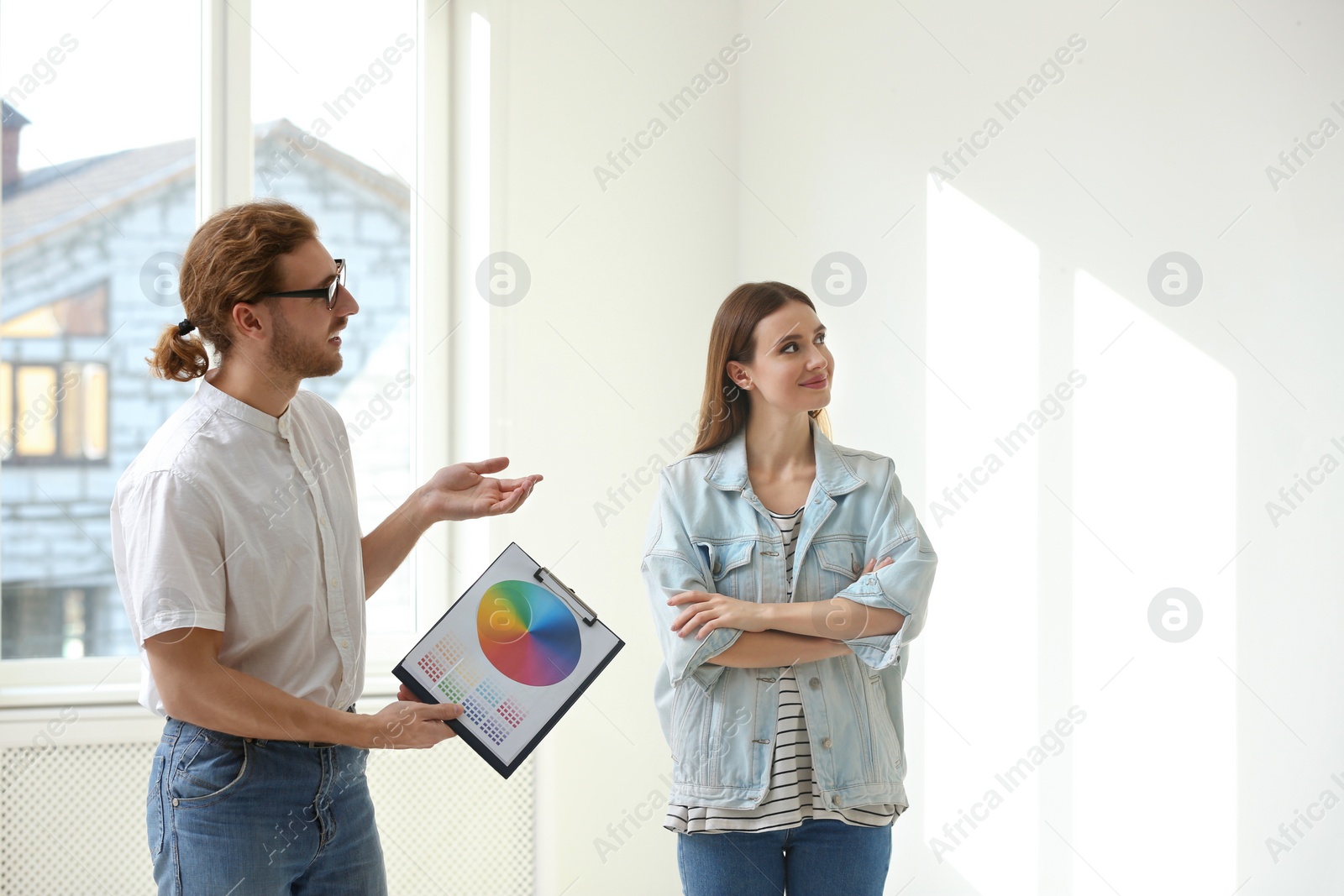 Photo of Professional interior designer consulting woman in empty apartment