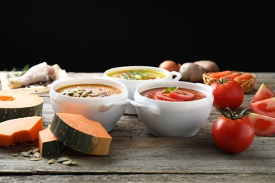 Tasty broth, cream soups in bowls and ingredients on old wooden table