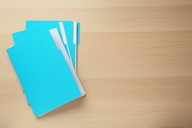 Photo of Turquoise files with documents on wooden table, top view. Space for text