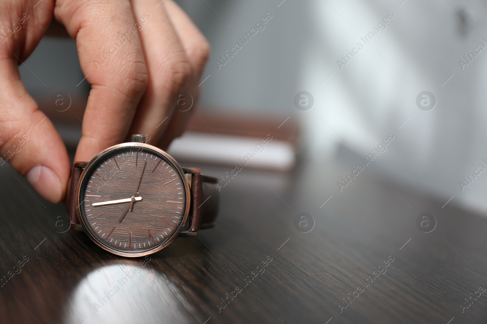 Photo of Man putting luxury wrist watch on table, closeup. Space for text