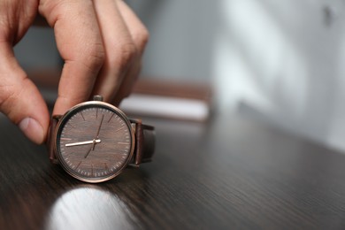 Photo of Man putting luxury wrist watch on table, closeup. Space for text