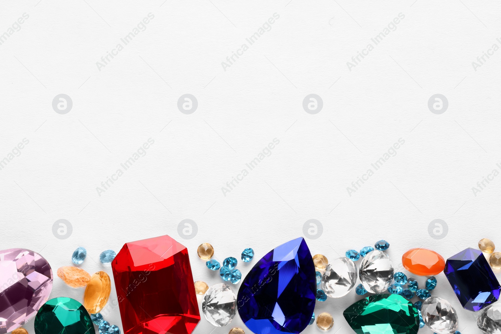 Photo of Different beautiful gemstones for jewelry on white background, top view. Space for text