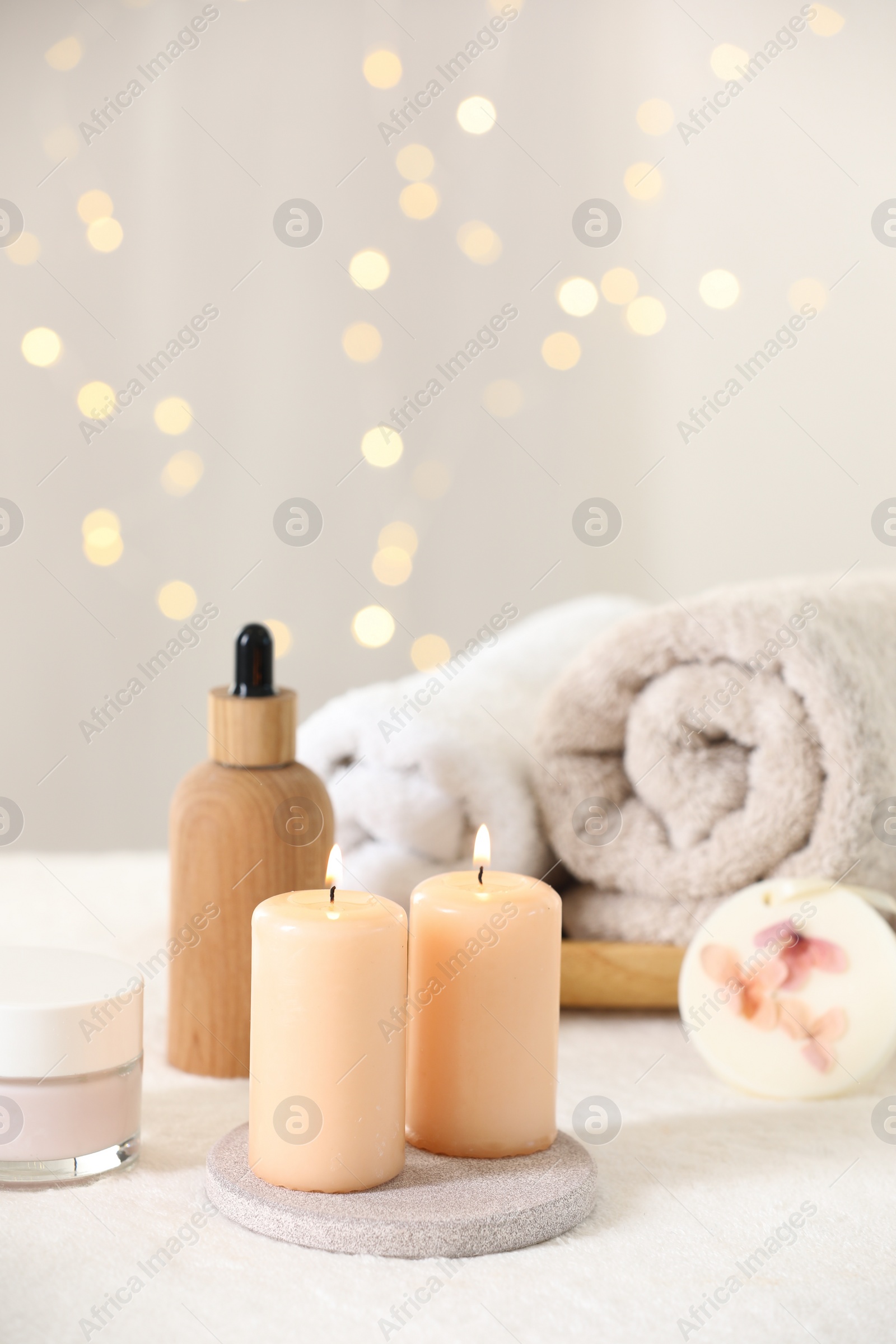 Photo of Spa composition. Burning candles and personal care products on soft white surface