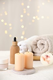 Spa composition. Burning candles and personal care products on soft white surface