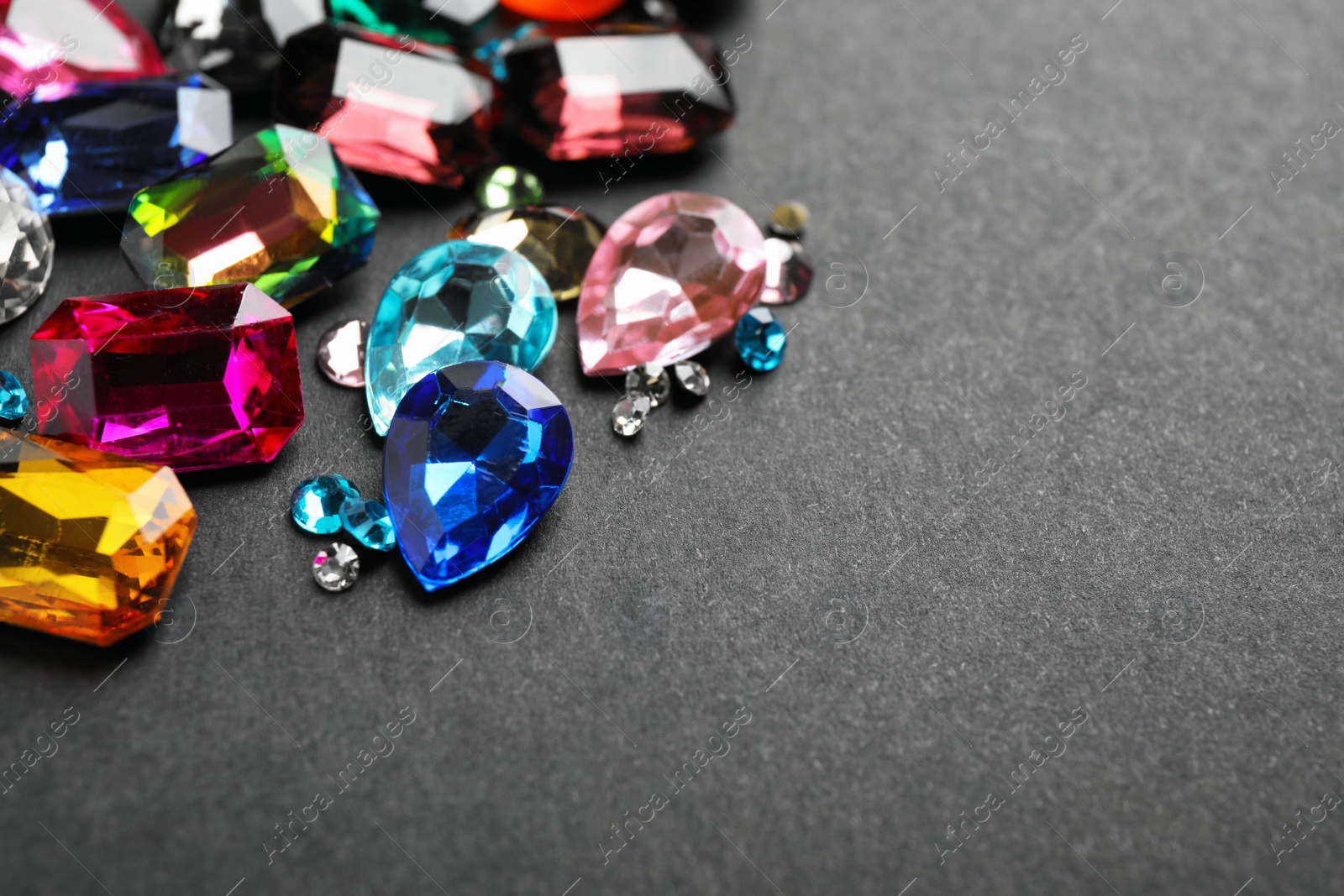 Photo of Different beautiful gemstones on black background. Space for text