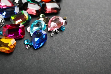 Different beautiful gemstones on black background. Space for text