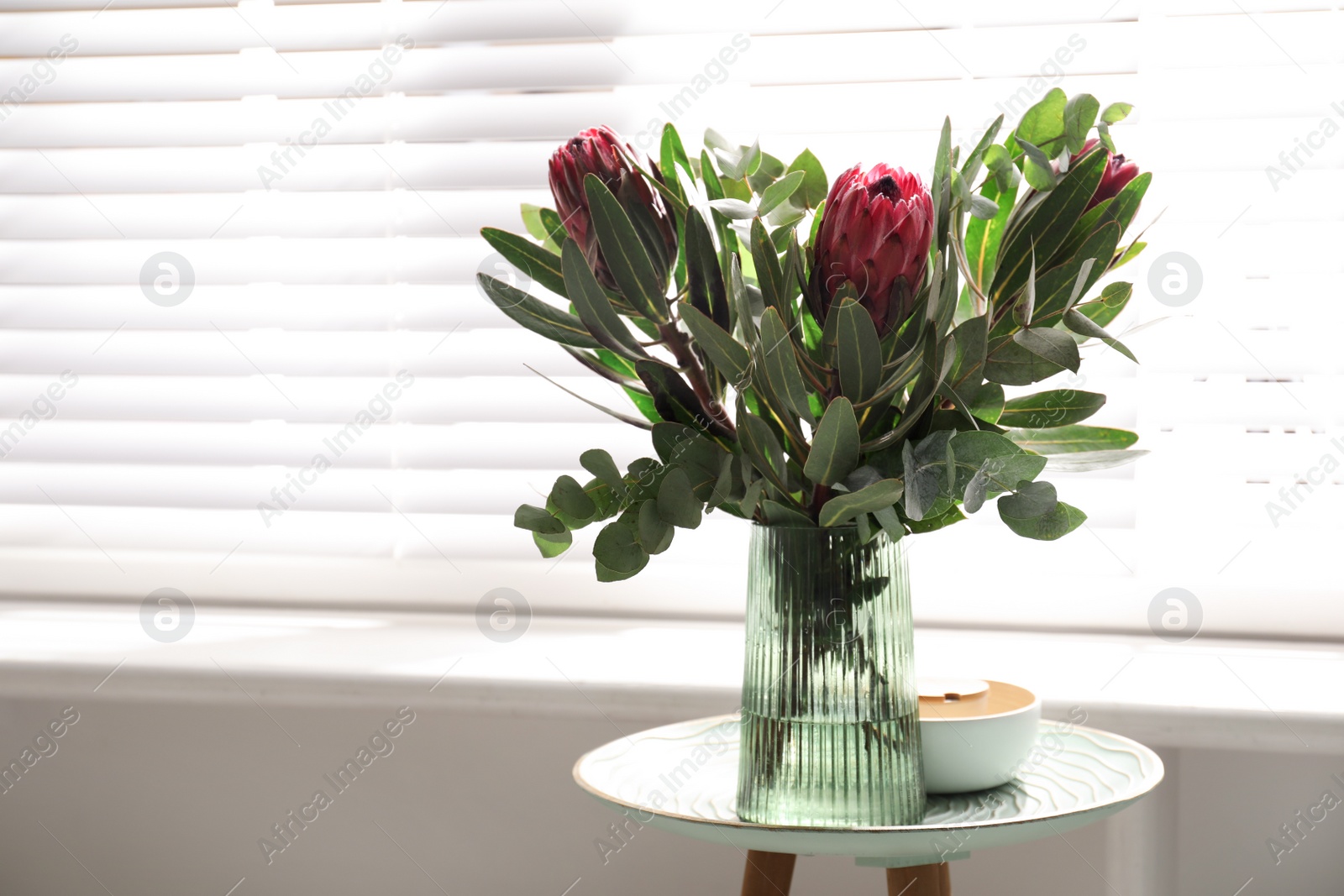 Photo of Vase with bouquet of beautiful Protea flowers on table indoors