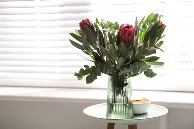 Vase with bouquet of beautiful Protea flowers on table indoors