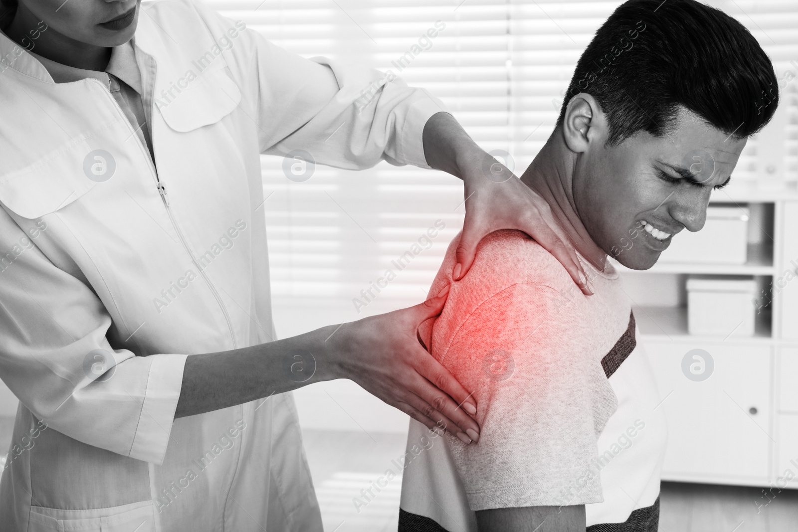 Image of Doctor examining man with shoulder pain in hospital