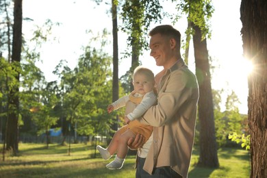 Photo of Father with his cute daughter spending time together in park on summer day, space for text