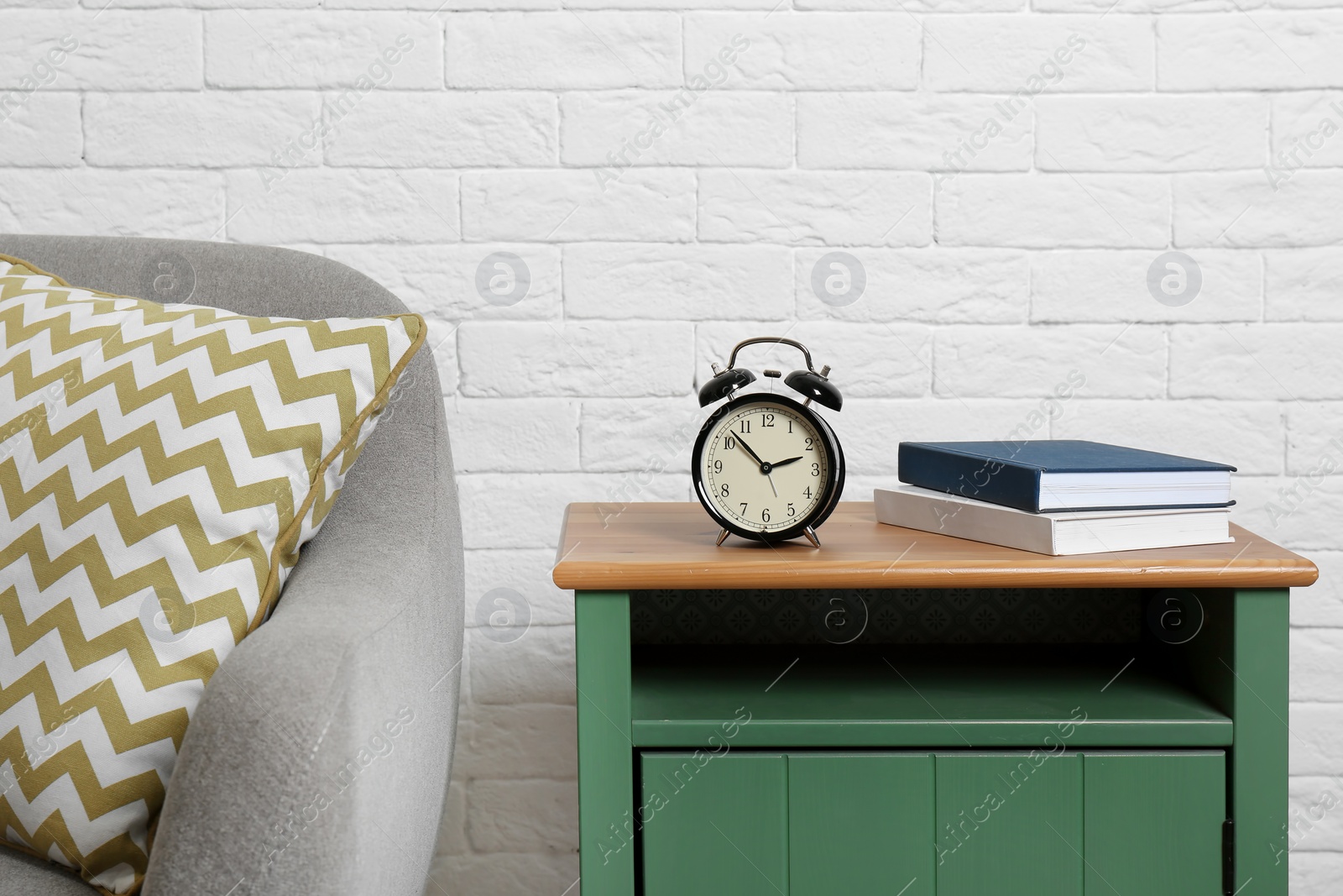 Photo of Analog alarm clock on side table in living room. Time of day