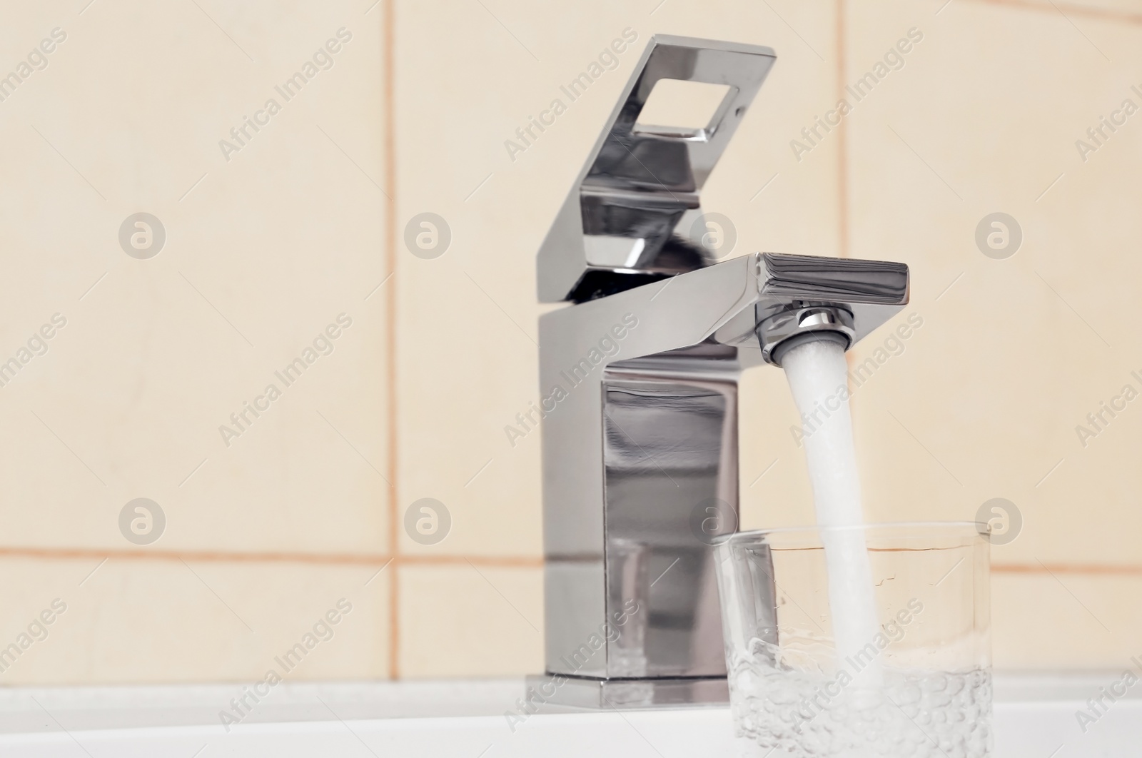Photo of Closeup view of filling glass with water from faucet indoors. Space for text