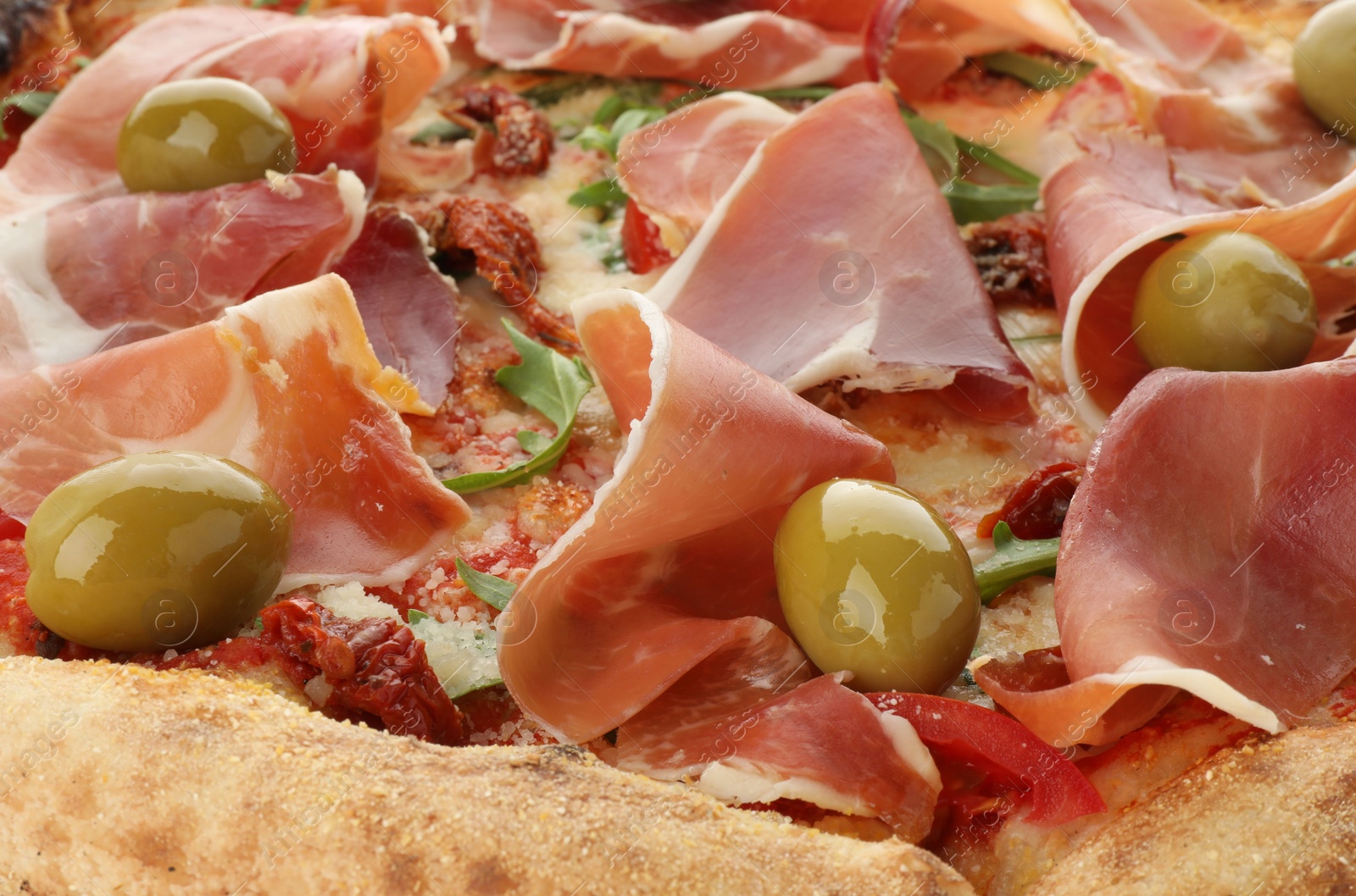 Photo of Tasty pizza with cured ham, olives and sun-dried tomato as background