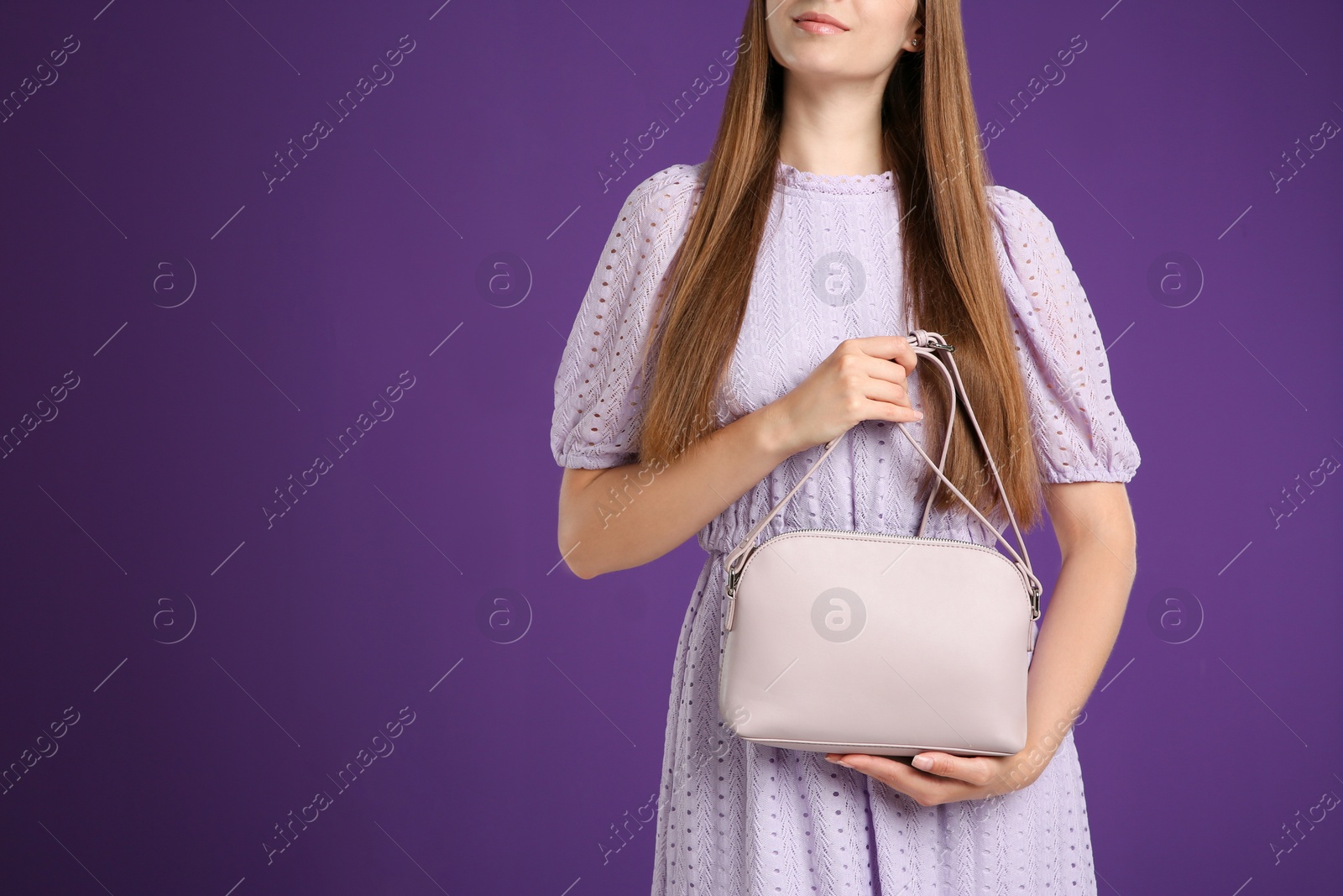 Photo of Young woman with stylish pink bag on purple background, closeup. Space for text