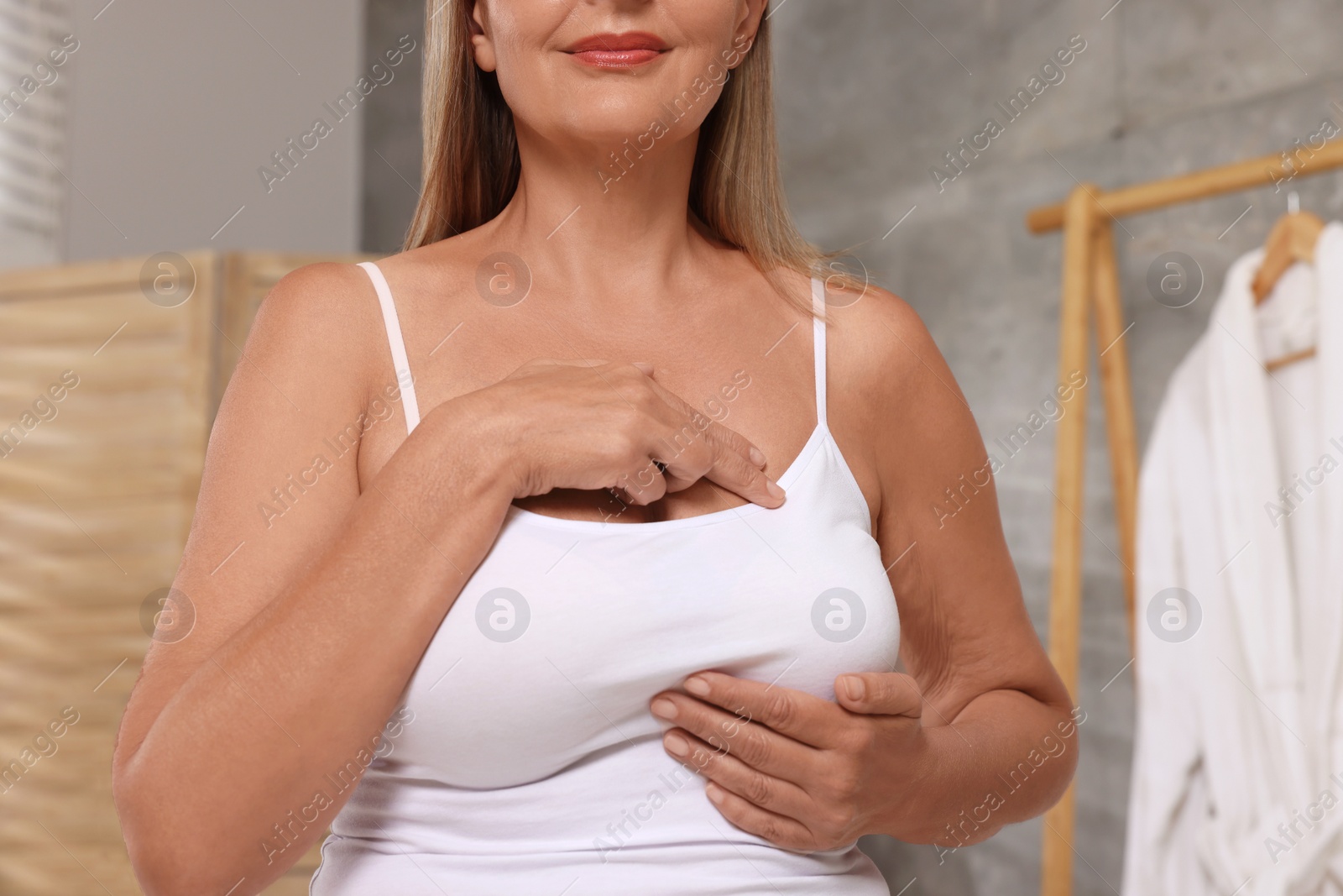 Photo of Woman doing breast self-examination in bathroom, closeup