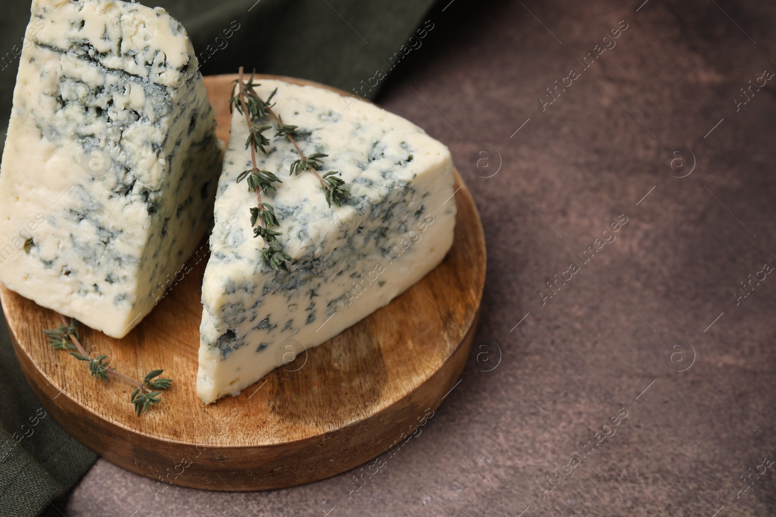 Photo of Tasty blue cheese with thyme on brown table. Space for text