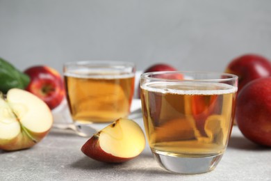 Photo of Delicious cider and ripe apples on grey table. Space for text