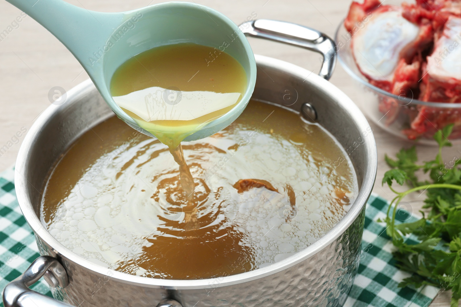 Photo of Delicious homemade bone broth and ingredients on table, closeup view