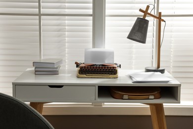 Photo of Comfortable writer's workplace with typewriter on desk in front of window