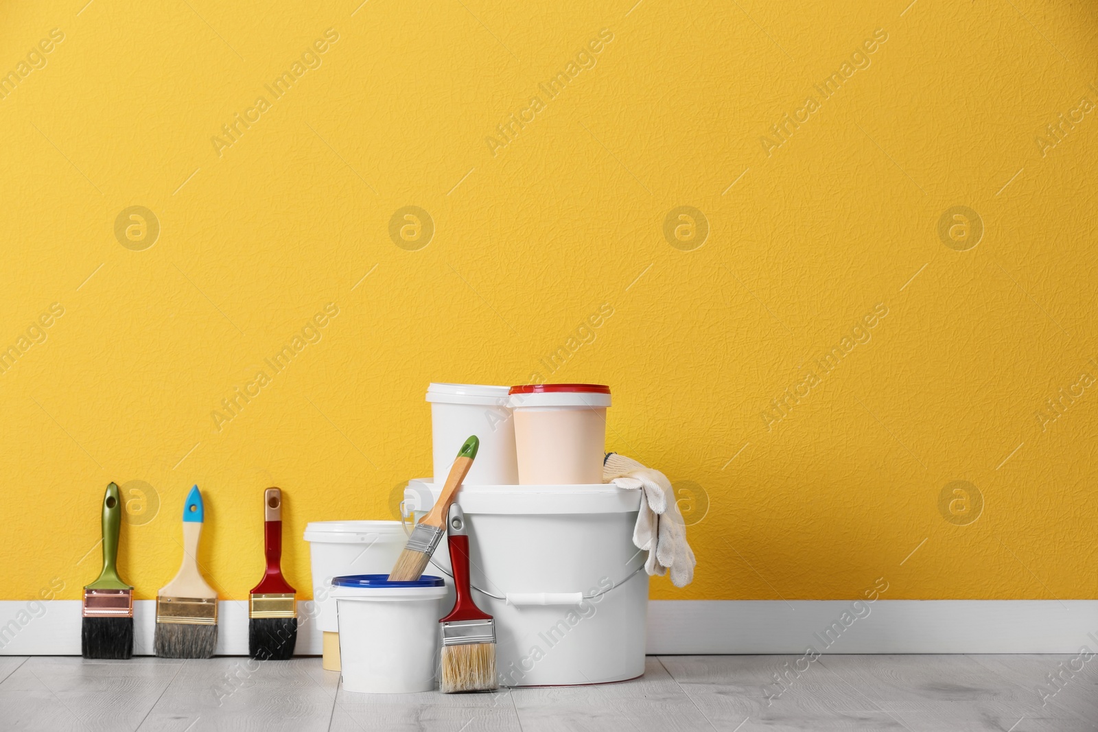 Photo of Set with decorator tools and paint on floor near color wall