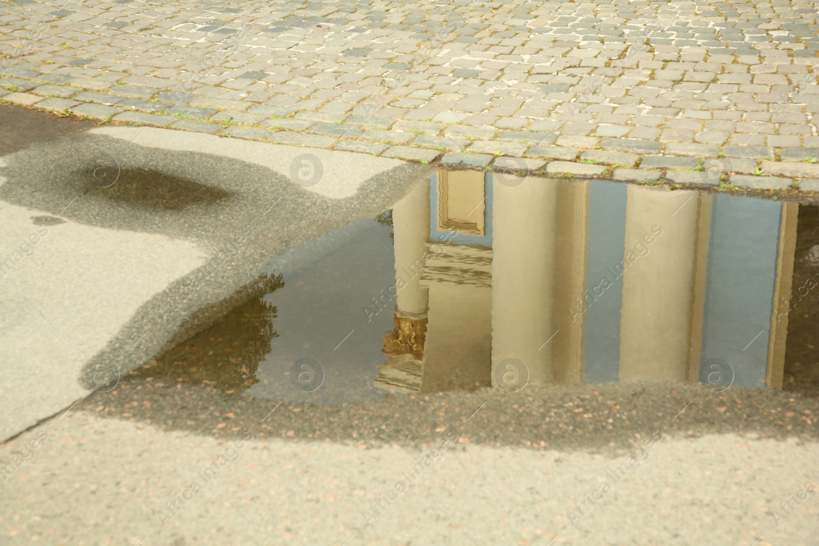 Photo of Reflection of beautiful building in puddle on asphalt