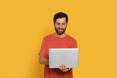 Photo of Handsome man with laptop on orange background