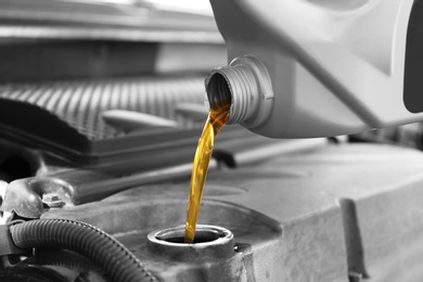 Photo of Pouring oil into car engine, closeup