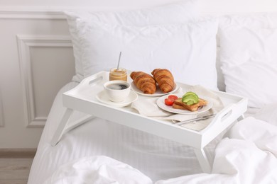 Photo of Good morning. Tray with tasty breakfast on bed at home
