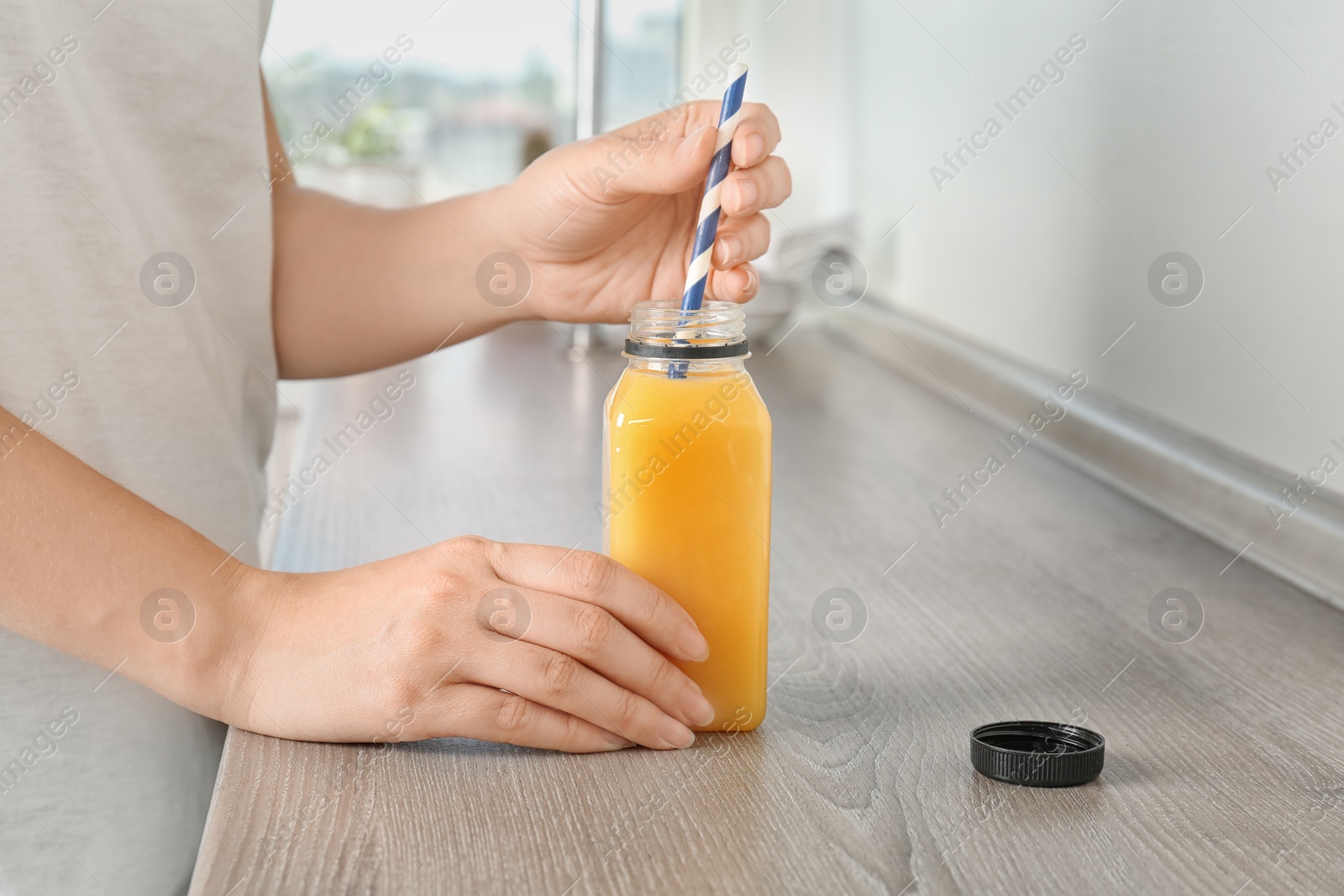 Photo of Woman with bottle of tasty juice at table