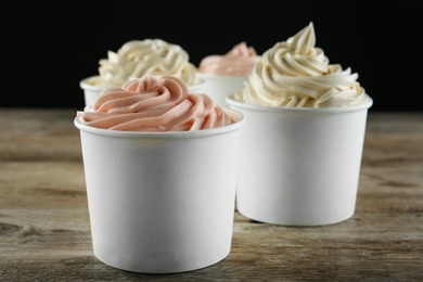 Cups with tasty frozen yogurt on wooden table